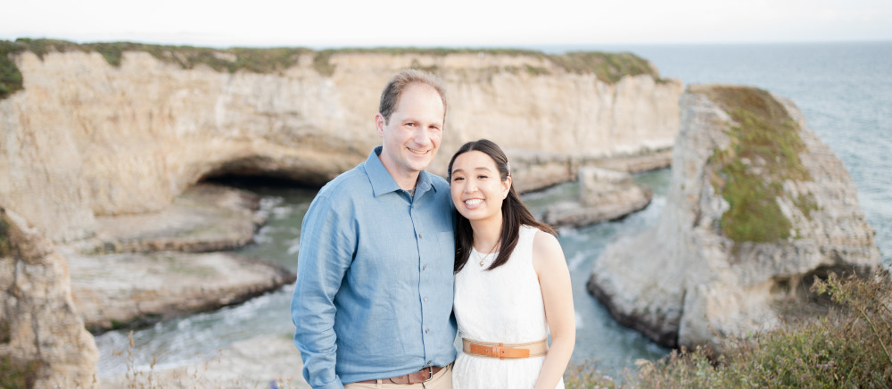 Chris and Ann posing for engagement photo above view of Pacific Ocean